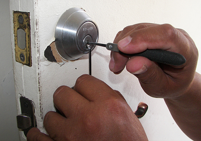 Locksmith picking commercial door lock.